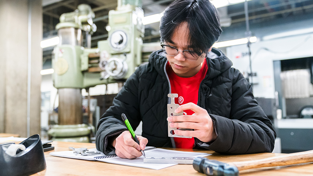 Machine manufactuing student writing down calculations