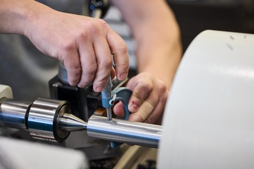 Close-up of a student measuring their work on the turning machine