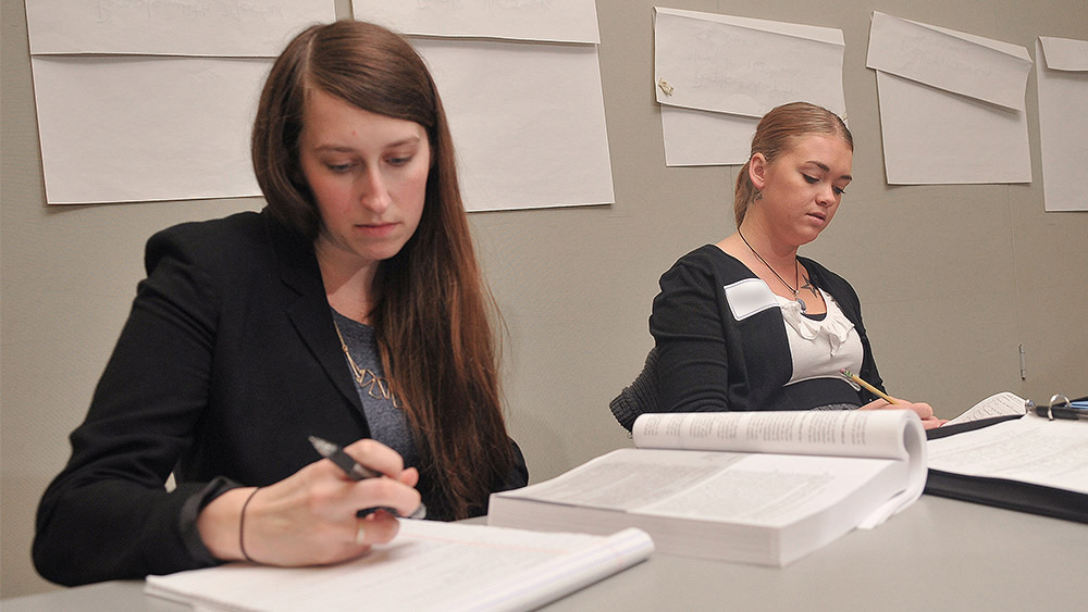 Students sitting in a classroom and writing in workbooks