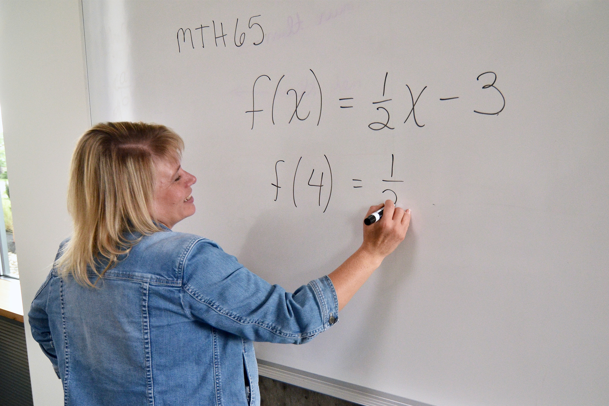 Math instructor writing equations on the whiteboard