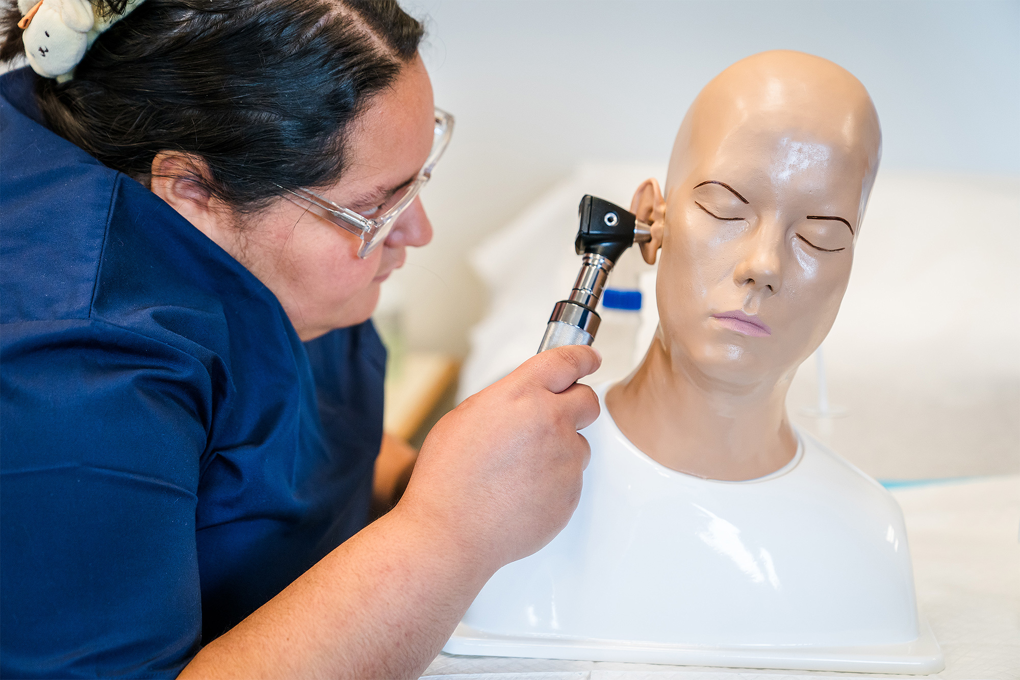Medical Assisting student examining a practice dummy's ear