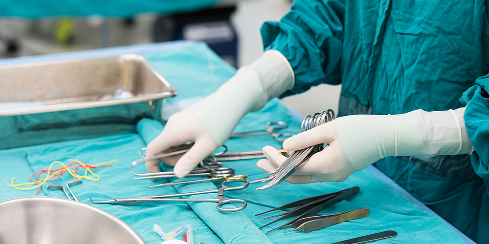 Gloved hands of a student are laying out sterile medical tools