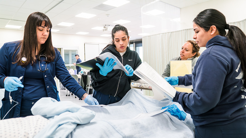 Students looking over a mock patient's charts and paperwork