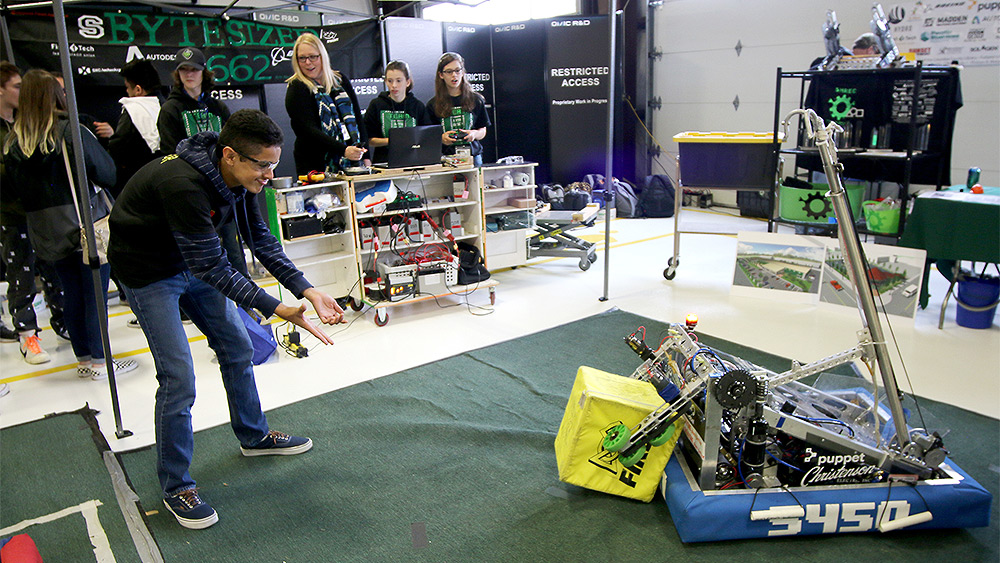 Students at an event interacting with a robot carrying a box