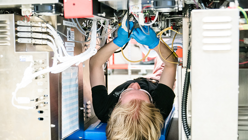 Microelectronics student working upside down in gloves