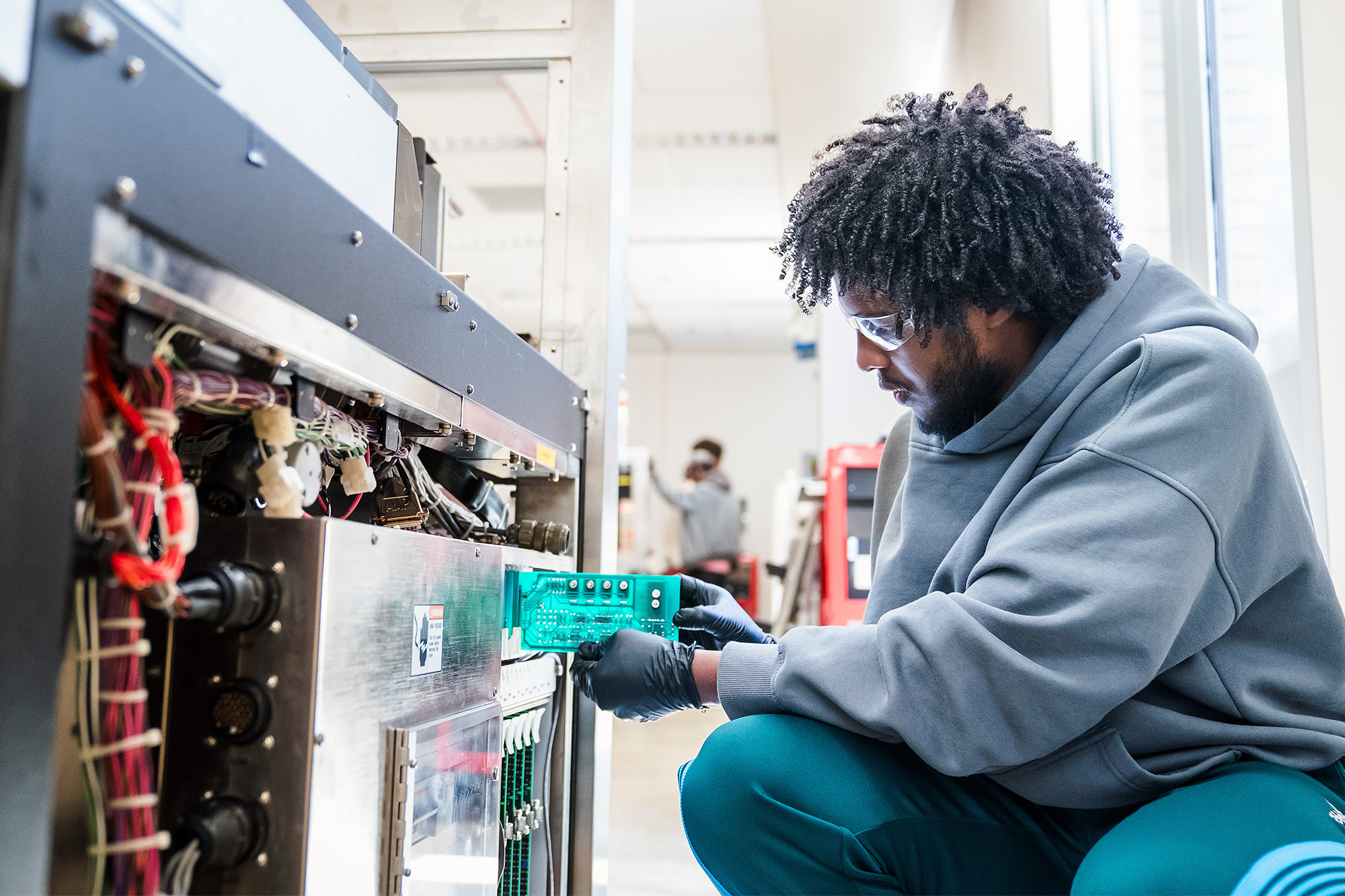 Microelectronics Technology student adjusting a silicon chip in a piece of equipment in equipment in the lab