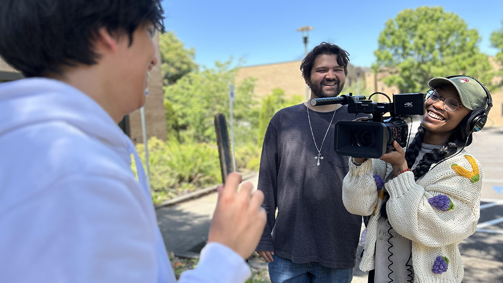 Three students making a video outside