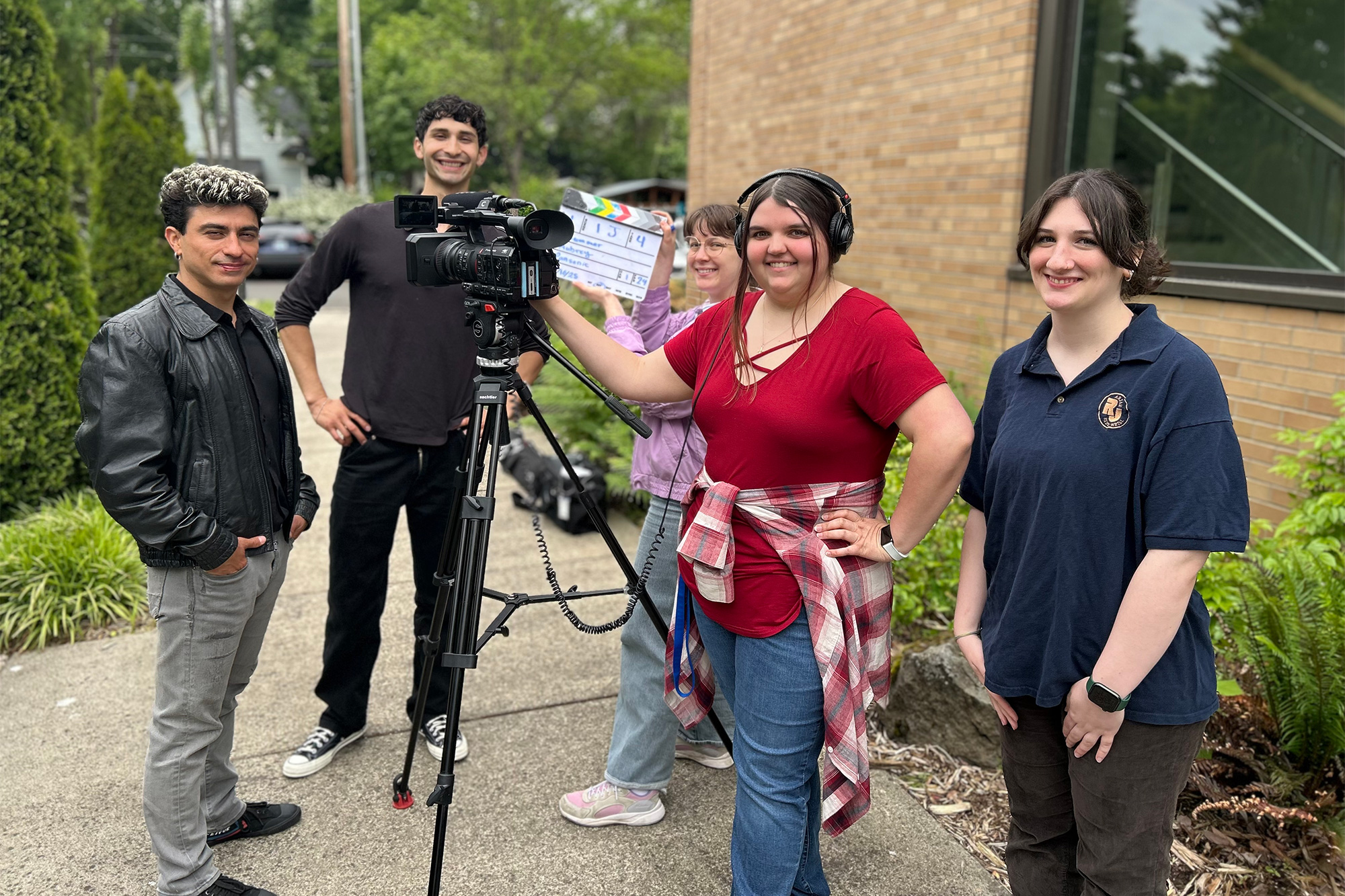 Multimedia students standing outside on campus with a video camera