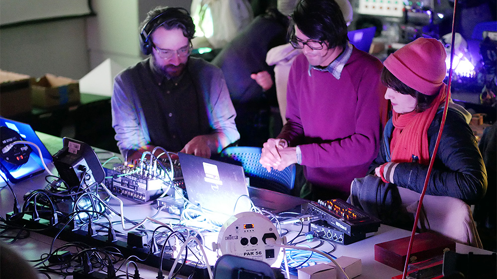 Students sitting with a computer and sound equipment in a lab