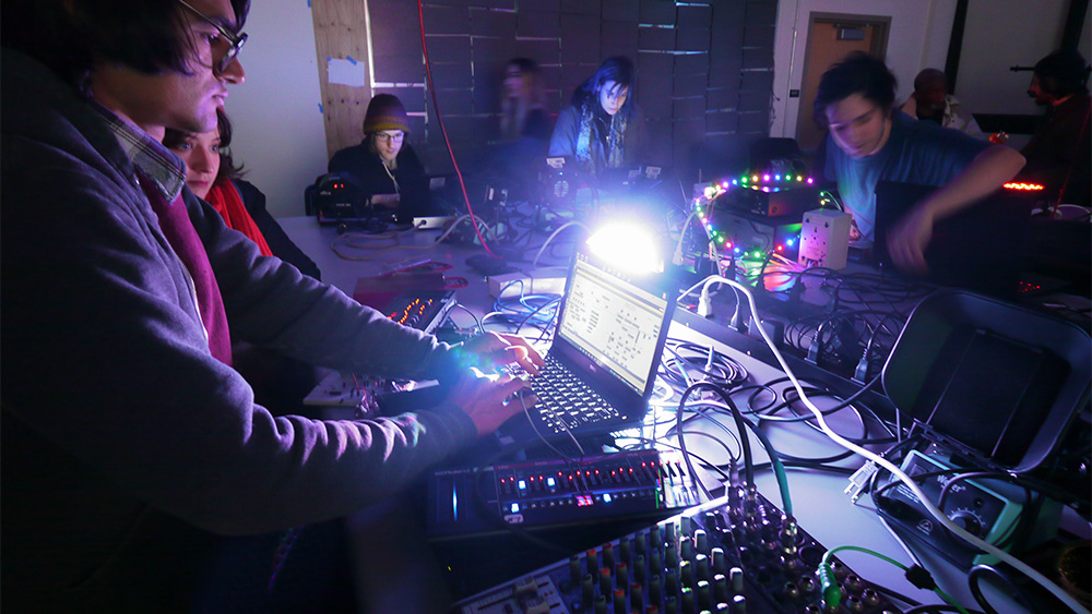 Students sitting with a computer and sound equipment in a lab