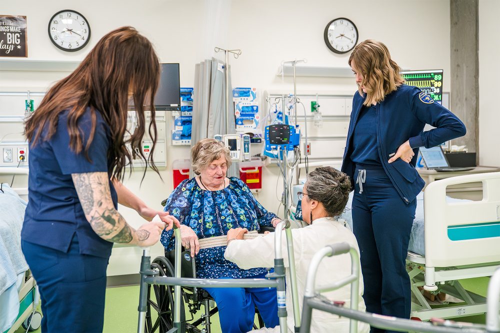 Nursing Assistant students helping get a patient out of a wheelchair