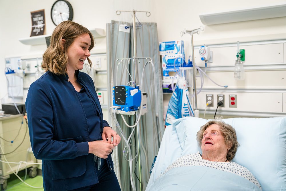Nursing Assistant student talking to a patient in bed