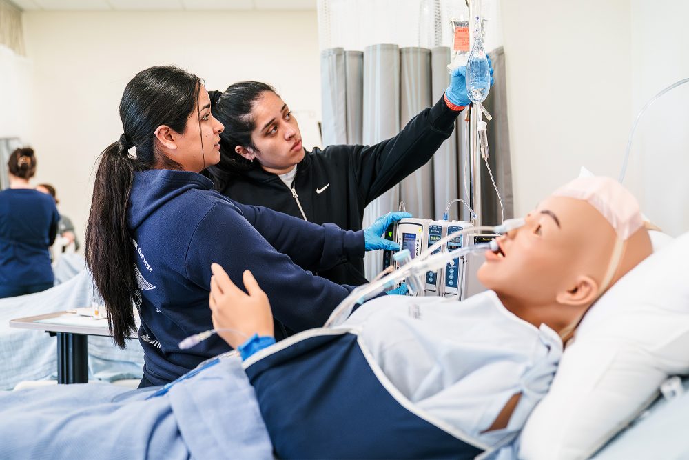 Nursing students looking at a mock patient's IV bag