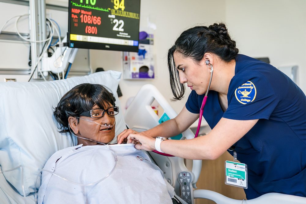 Nursing student checking a mock patient's respirator