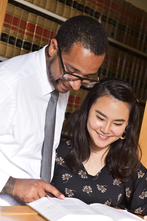 Instructor and student looking at a book together in the paralegal library