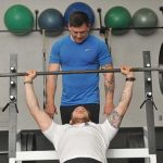 Instructor helping a student weightlift at Sylvania