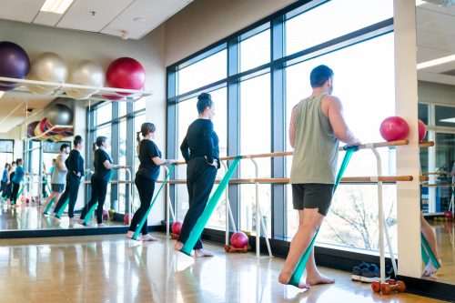 Students stretching their legs at a barre