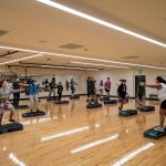 workout studio with hardwood floor and students stretching