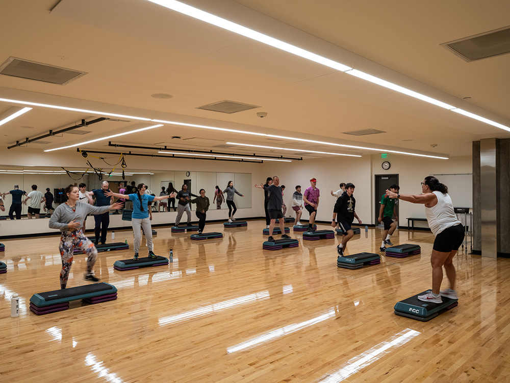 workout studio with hardwood floor and students stretching