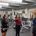students with phone taking picture with weight machines