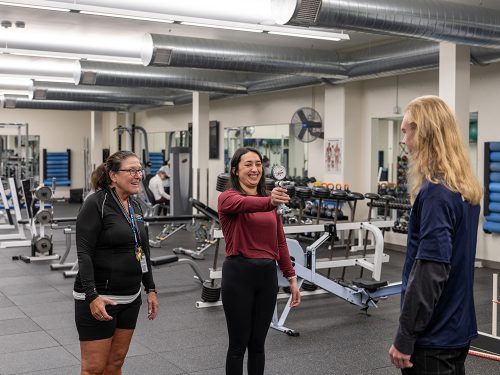students with phone taking picture with weight machines