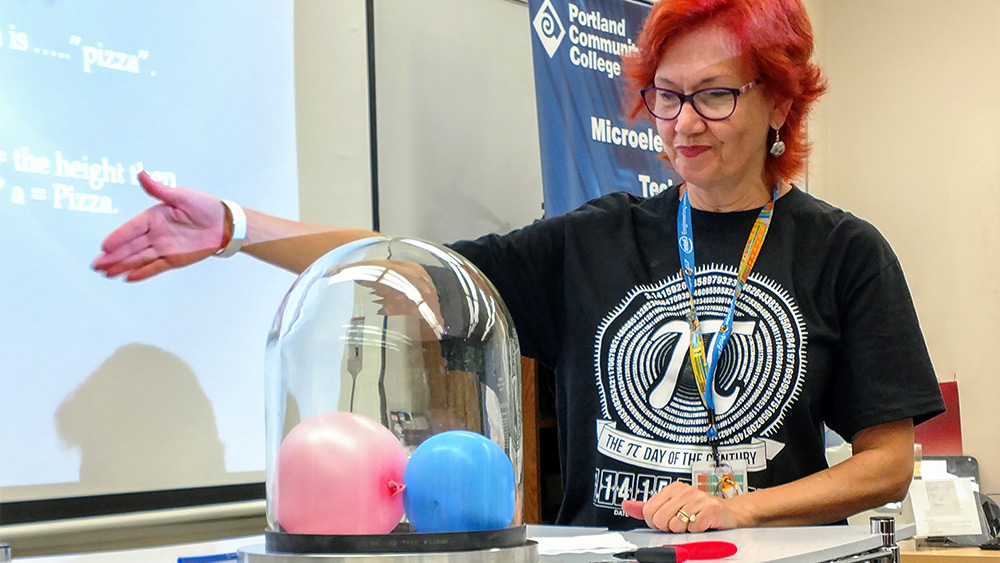 Instructor doing a physics experiment at the front of a classroom