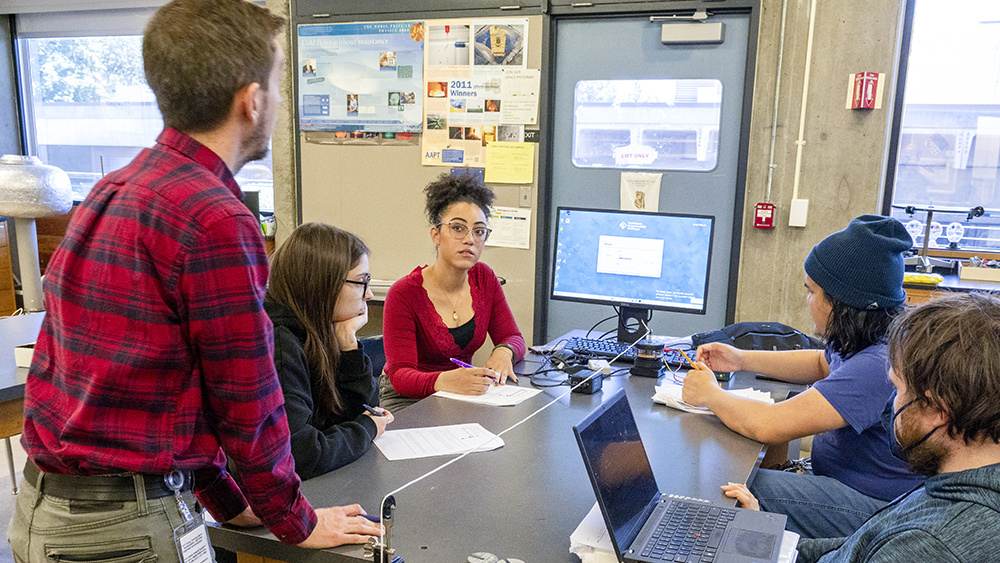 Physics instructor helping small group with a project