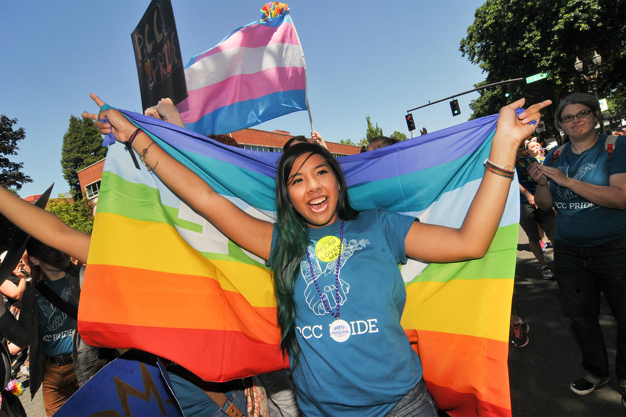 Student of color holding pride flag and wearing PCC shirt at the Portland Pride parade