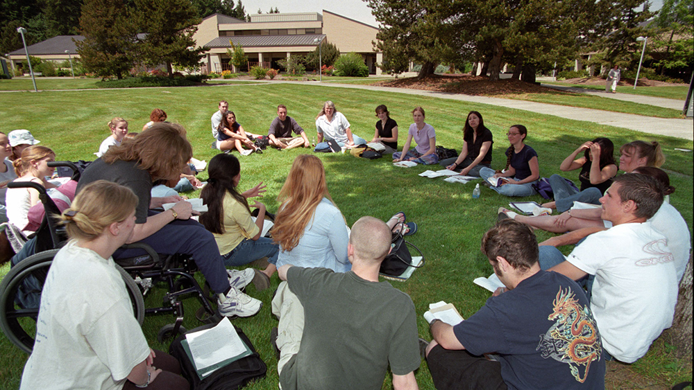 Students sitting outside in the grass for a class