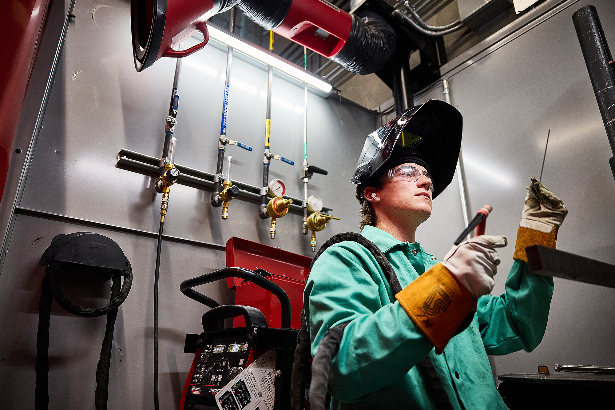 Student holding her wire welding equipment in the welding booth