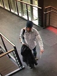 white male, 40-50 years old, wearing a blue beanie, white/light colored long sleeve dress shirt, jeans, carrying a yellow/black backpack with a green clip