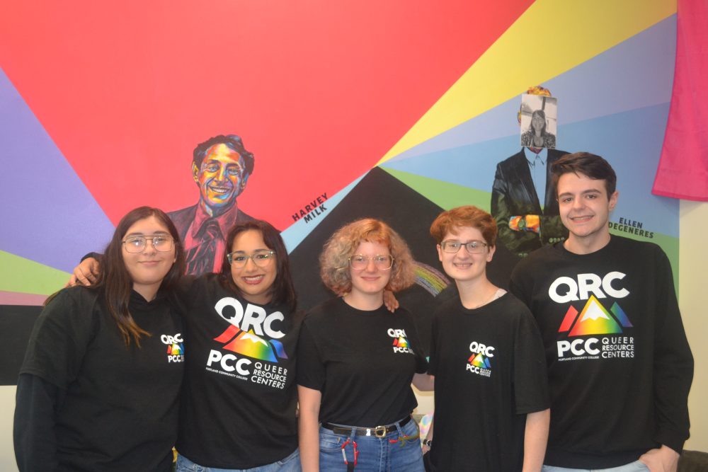 five students in QRC t-shirts standing in front of a colorful wall