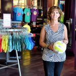 Owner of Aries Apparel athletic wear standing holding volleyball in retail store