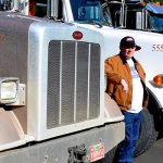 Bud Construction workers standing in front of parked, lined up semi trucks