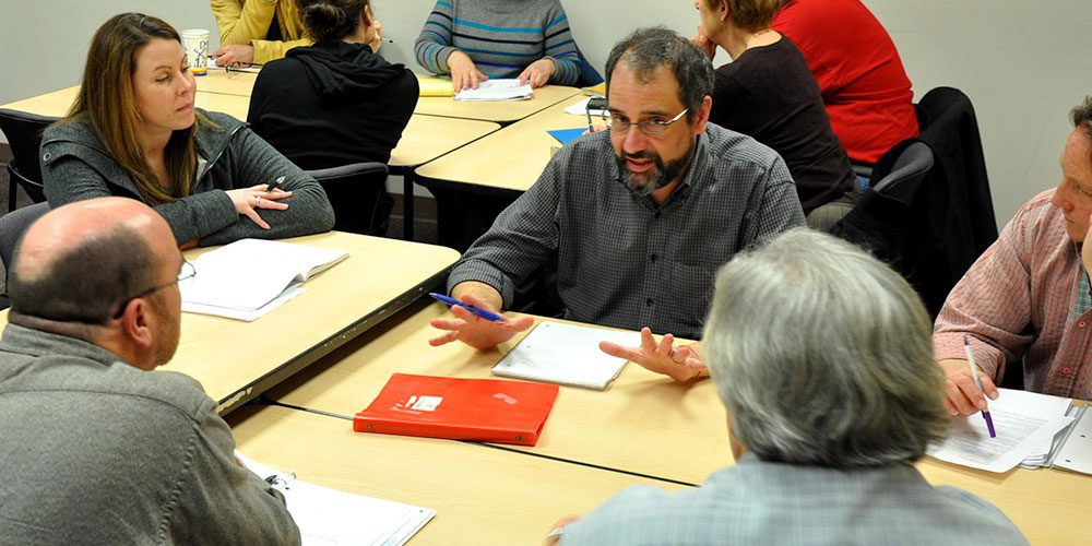 Group of people at table discusses business training in CLIMB classroom