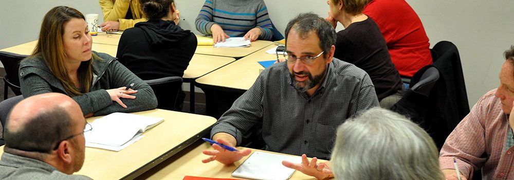 Group of people at table discusses business training in CLIMB classroom