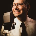 Man smiling next to a microphone