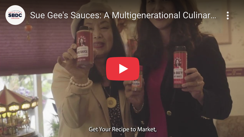 Two women smiling and holding sauce bottles