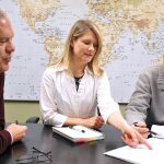 People looking over paperwork with a global map in the background