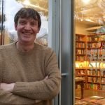 Christopher stands in front of his bookshop entrance