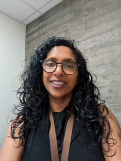 A picture of Anne Grey with glasses and wears a black top