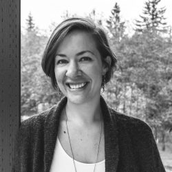 A black and white photo of Casey leaning against a post with trees in the background