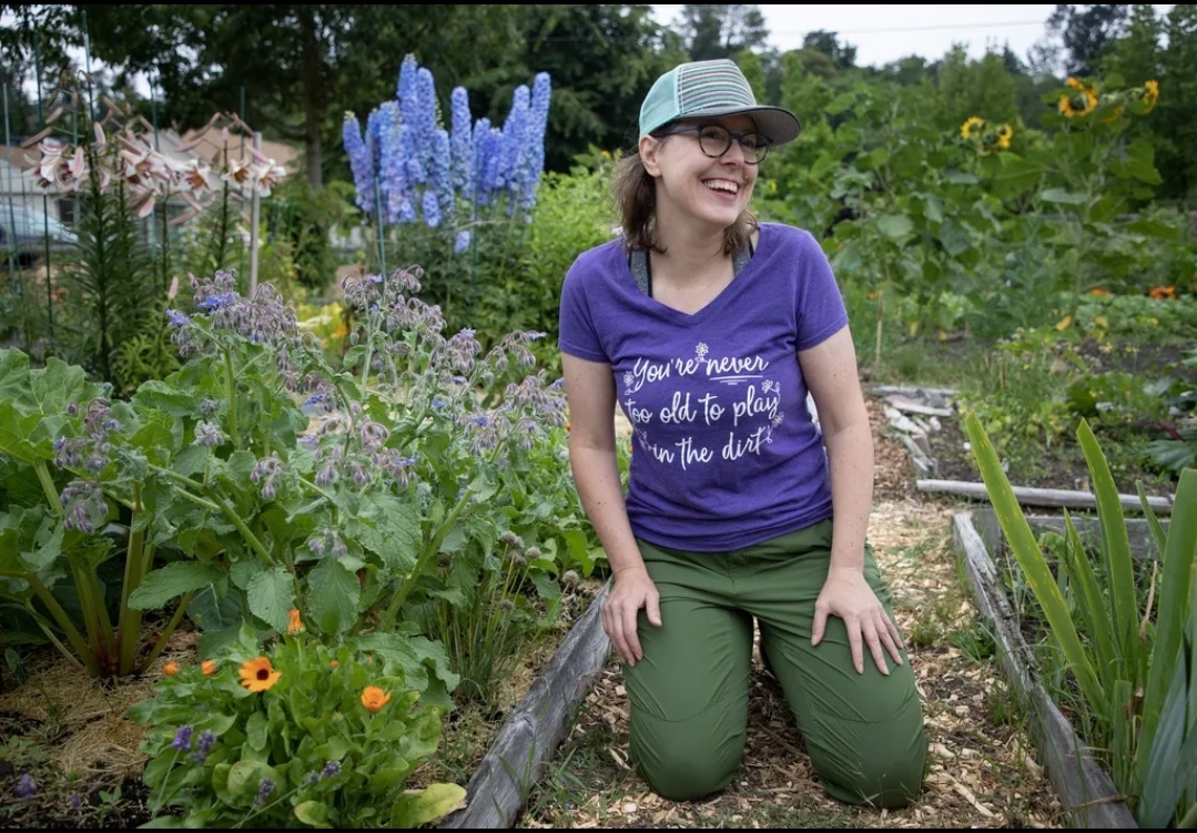 Instructor kneeling near her community garden plot in Seattle, WA. 