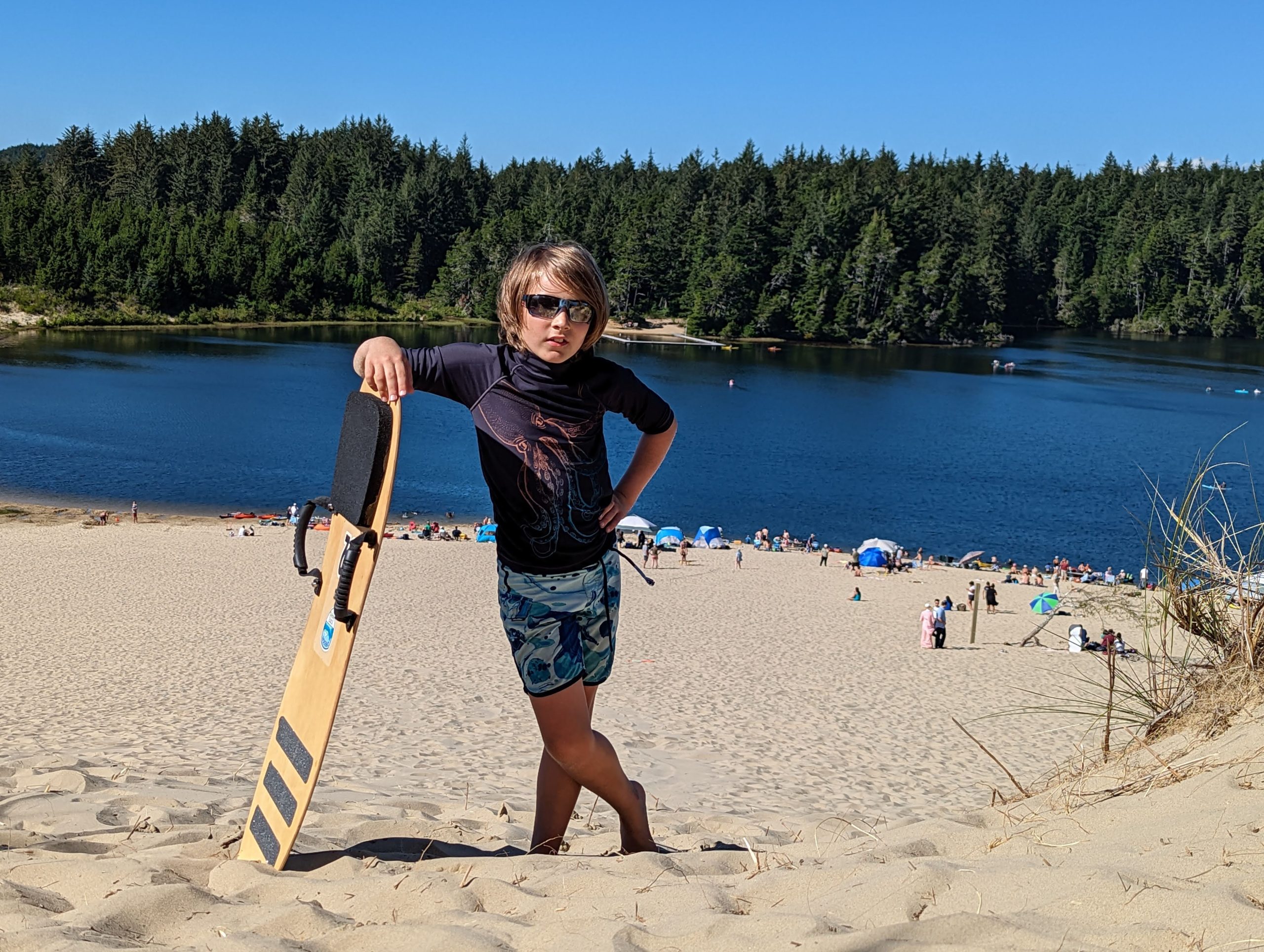 Janis's son leaning on a sandboard at a lake.
