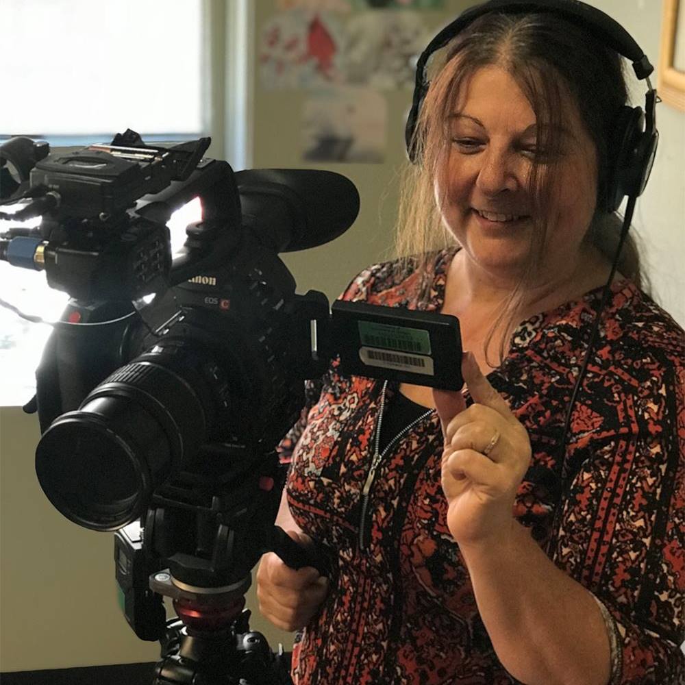 Mary Anne Funk wearing headphones while working a video camera