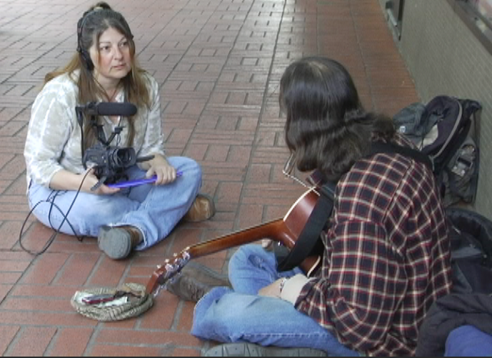 Mary Anne sits across from street artist, Will Dalgard, interviewing him about his story.