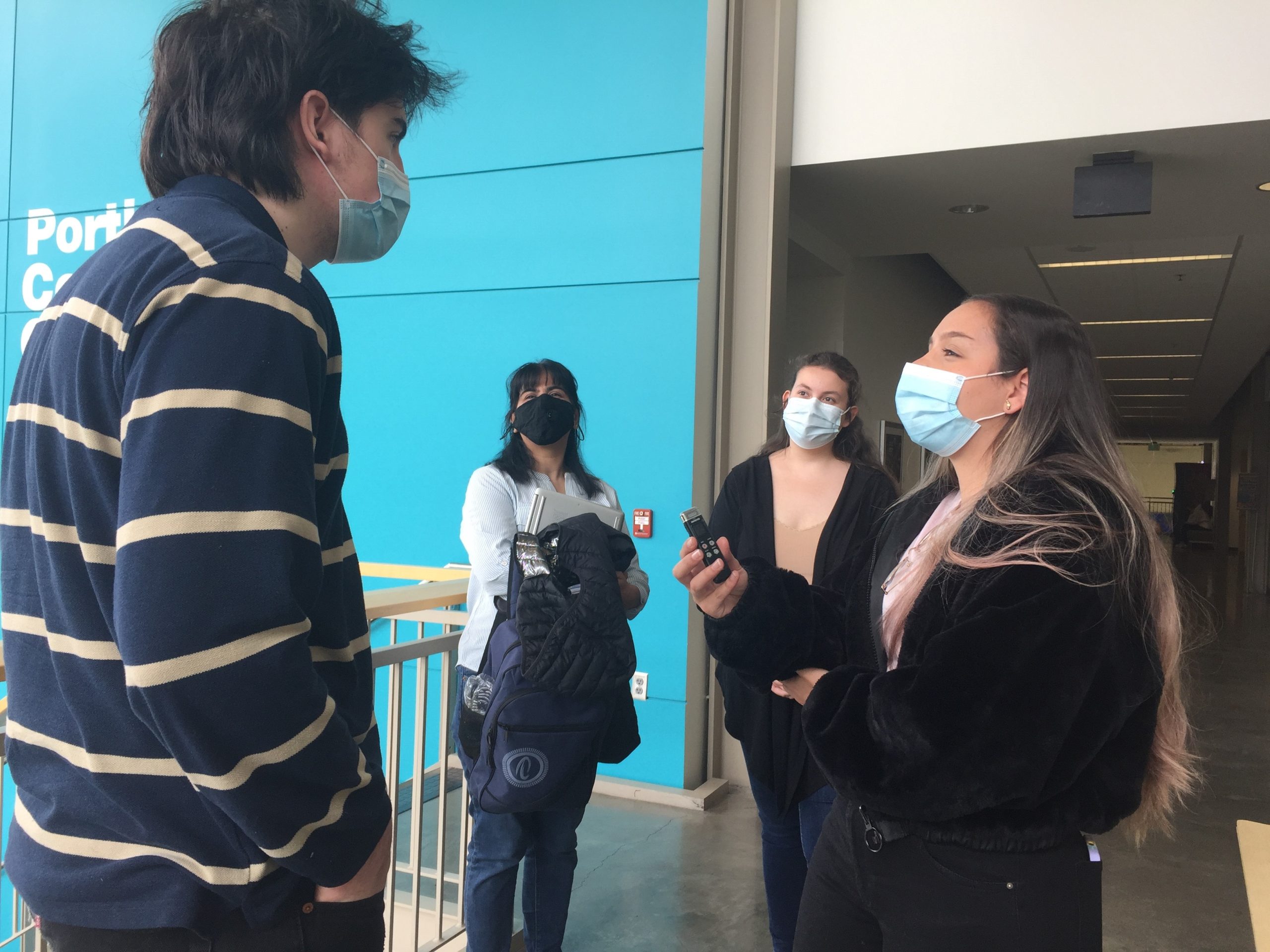 A group of students practice interviewing each other for an audio story.