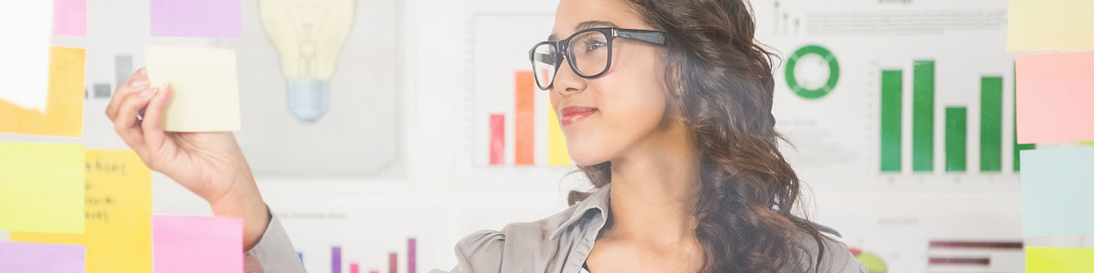 a woman looks at a sticky note with details about her project.