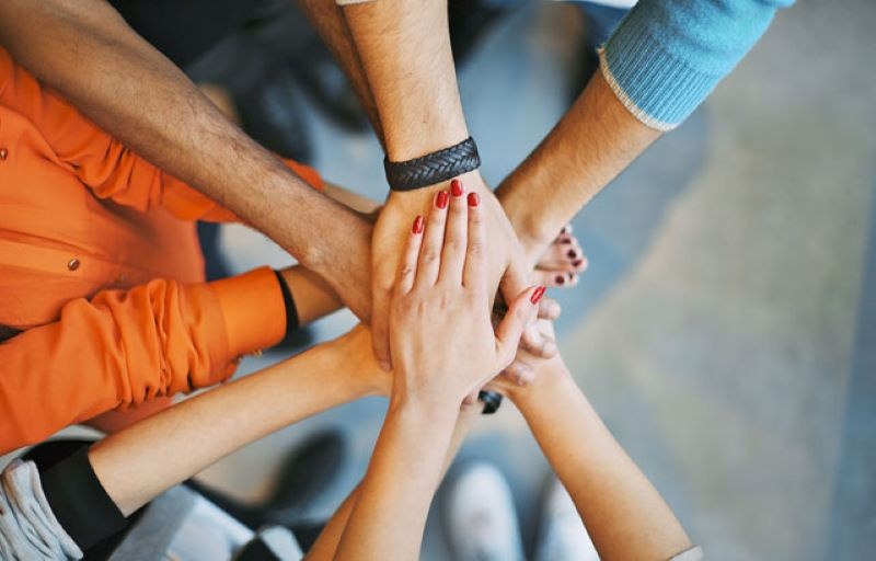 A diverse group of people overlapping their hands in a circle