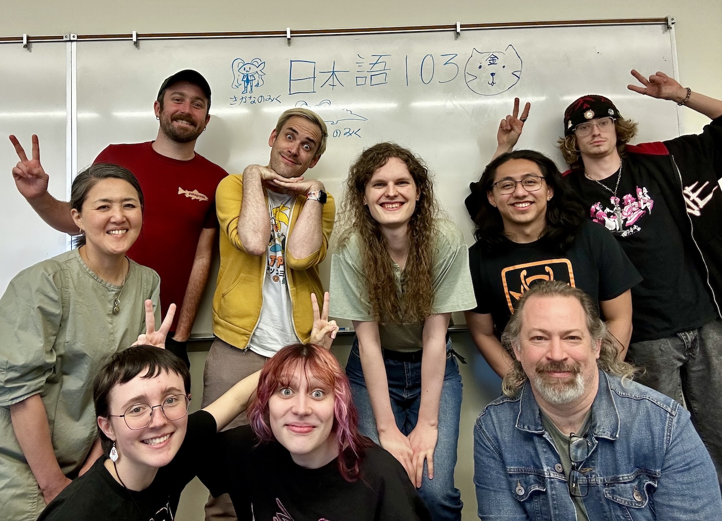 JPN 103 Students and Yumiko Omata posing in front of a classroom whiteboard